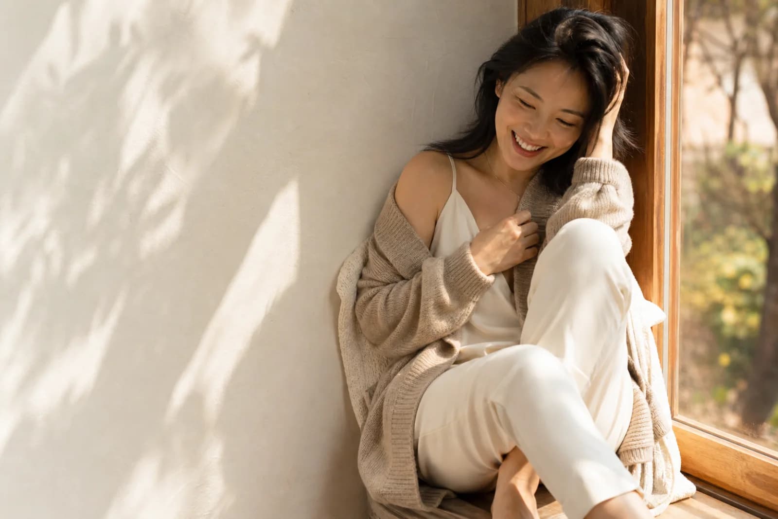 成年女性坐在阳光窗边自然微笑